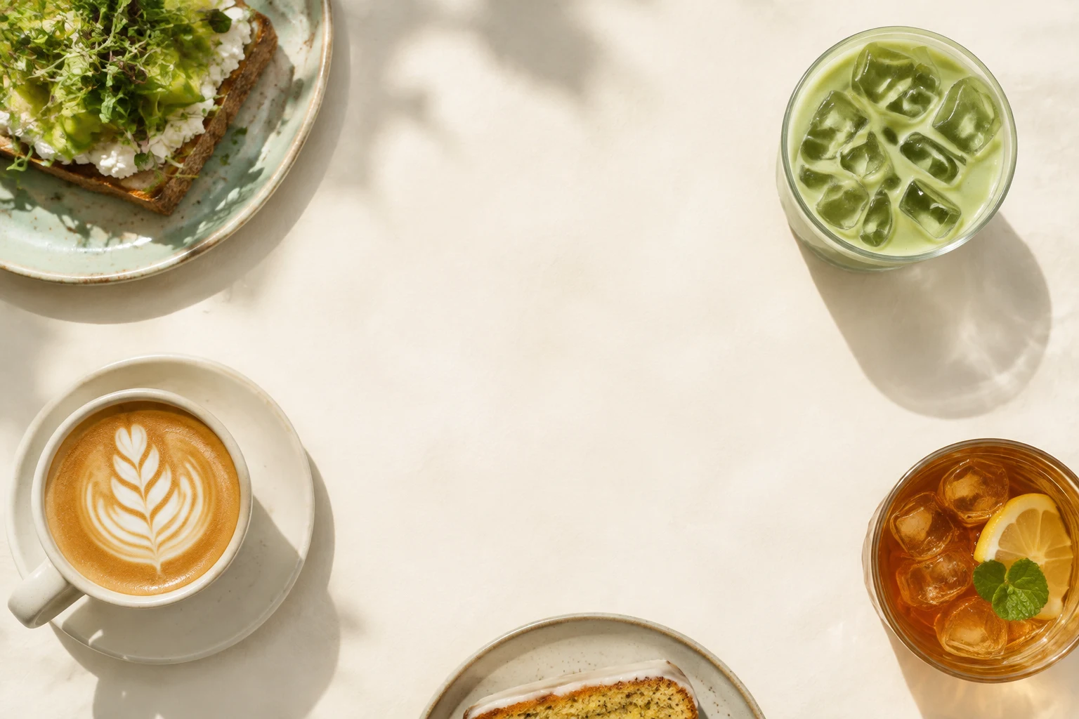 Ein heller Tisch mit Matcha, Cappuccino, Eistee, Stulle und Kuchen aus der Vogelperspektive – Bildkonzept